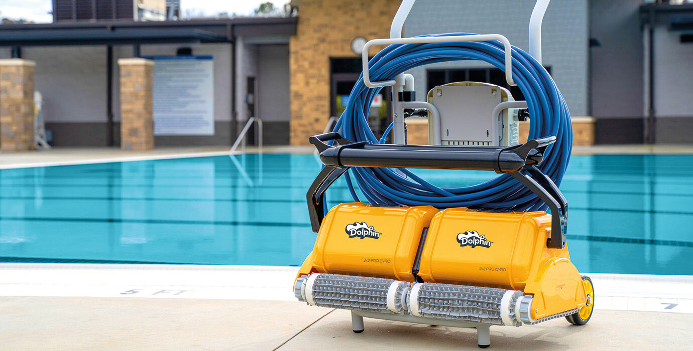 Yellow dolphin pool cleaning robot with blue hose coiled on a black metal cart.