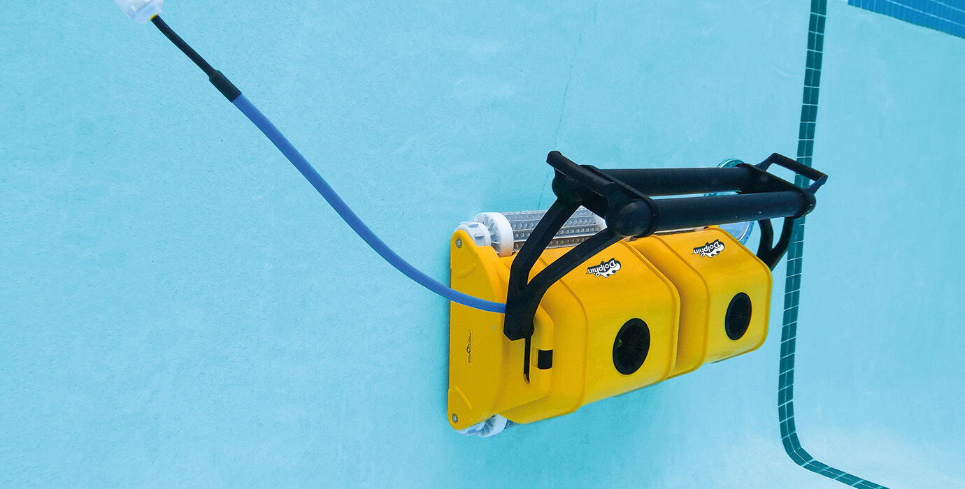 Yellow robotic pool cleaner with black handle and blue hose.