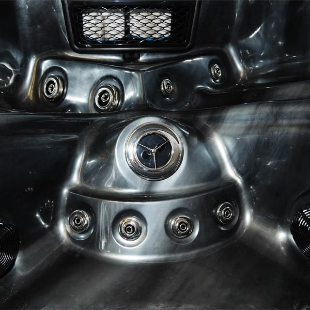 Shiny chrome-plated hot tub jet assembly with a central circular control dial and surrounding threaded nozzles.