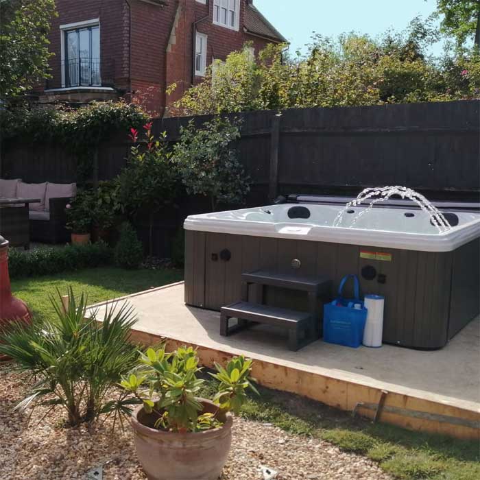 Gray and white hot tub with a water feature spraying from the top