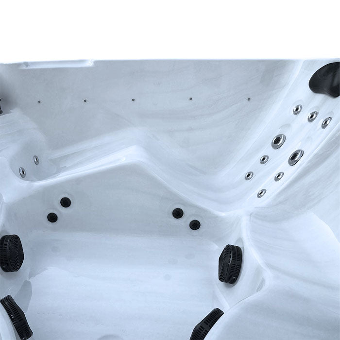 White hot tub with black jets and silver water feature nozzles.