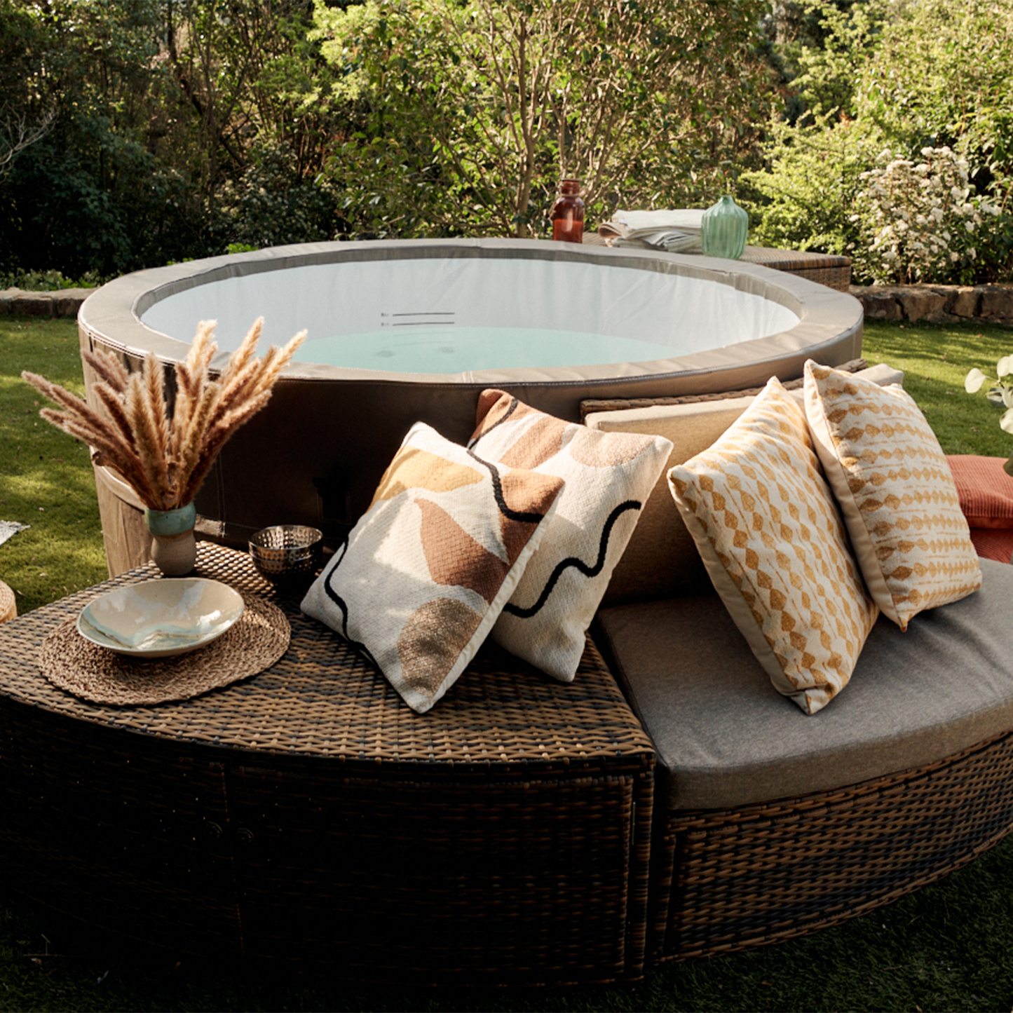 Circular outdoor hot tub with a gray rim and light blue water, surrounded by woven wicker furniture.