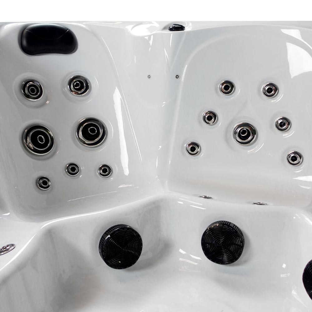 White hot tub with black jet nozzles and circular chrome fixtures.