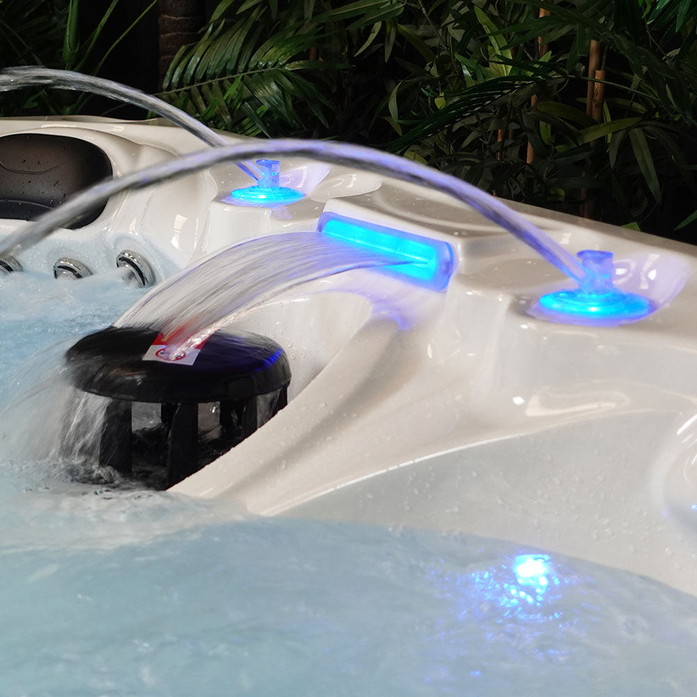 White hot tub with blue led lights and a waterfall feature.