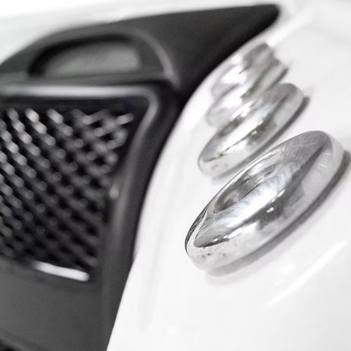 Silver circular knobs with a polished metallic finish, set against a white surface next to a black mesh grille.