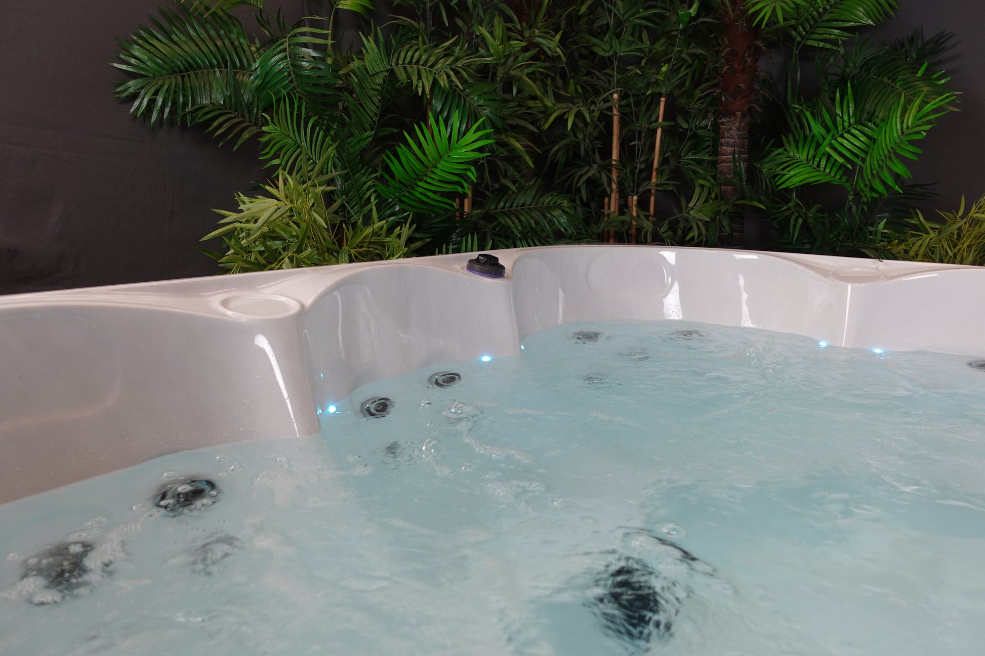 White acrylic hot tub with blue led lighting and black jet nozzles.