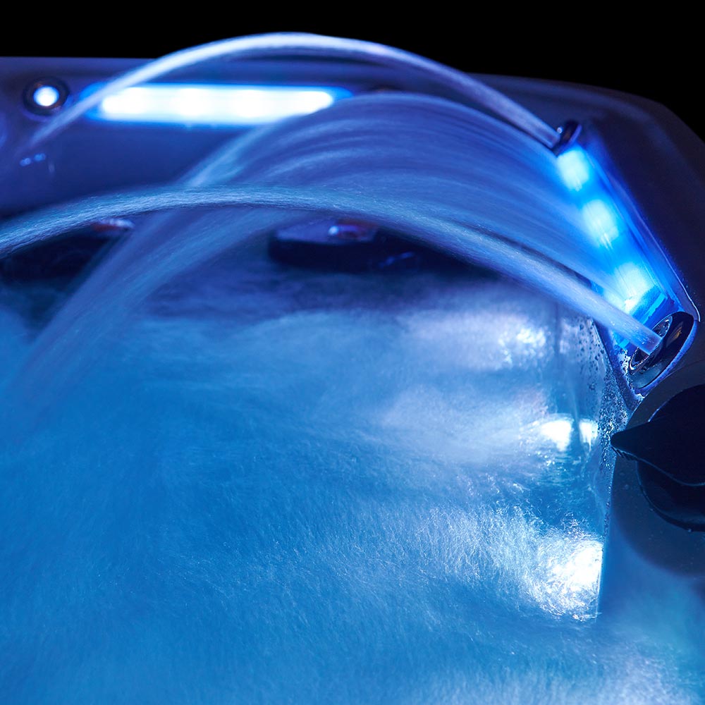 Blue led-lit water jet spout pouring into a hot tub.