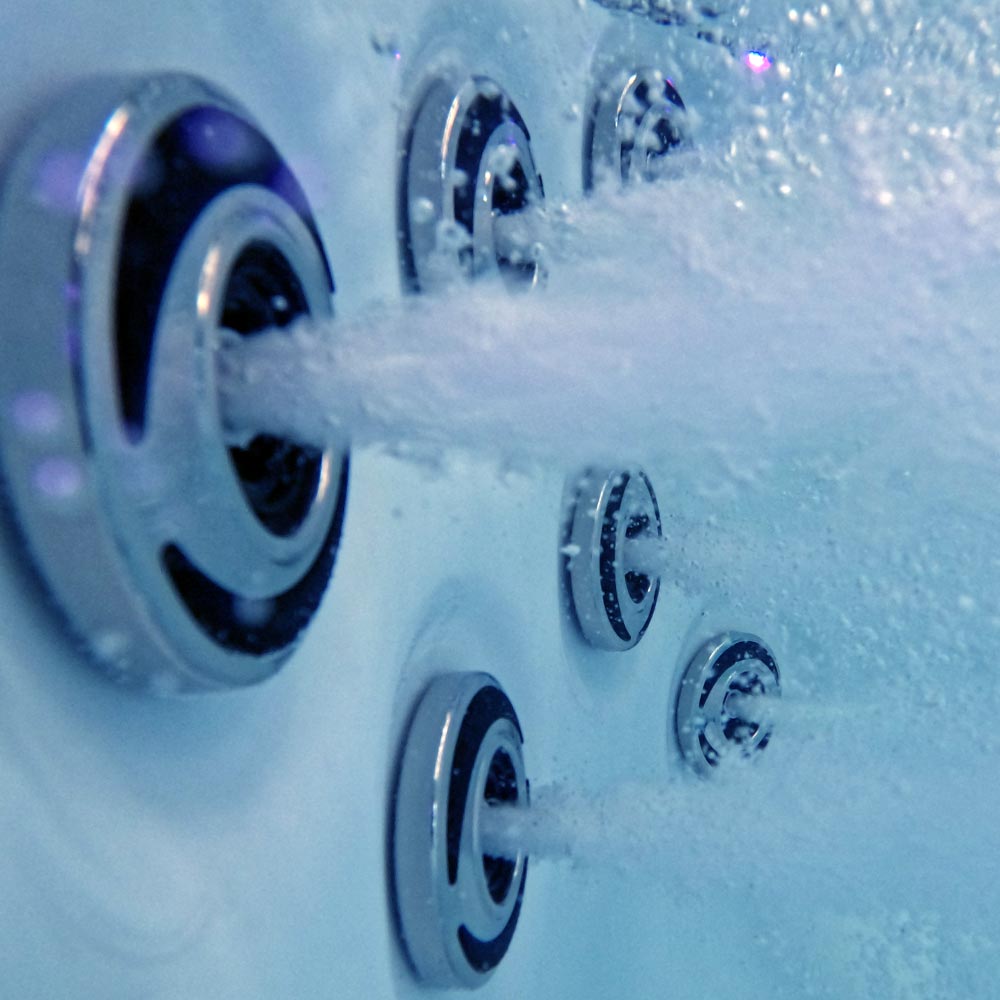 Chrome-finished jet nozzles with black accents spray water in a modern hot tub.