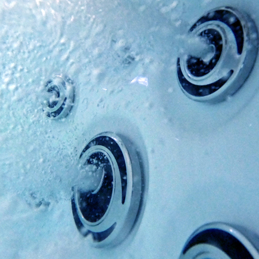 Silver-toned circular jet nozzles with black inner rings, embedded in a light blue water surface.