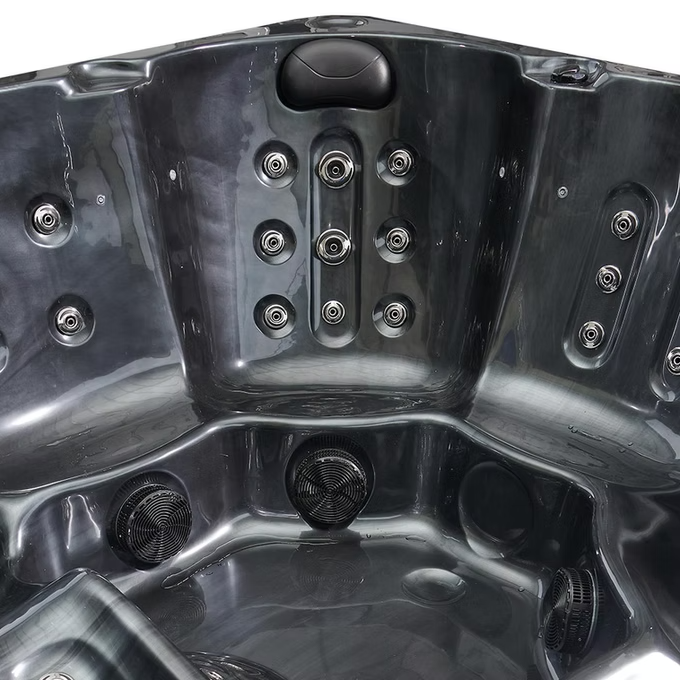 Black plastic hot tub with multiple jet nozzles and circular speaker grilles.