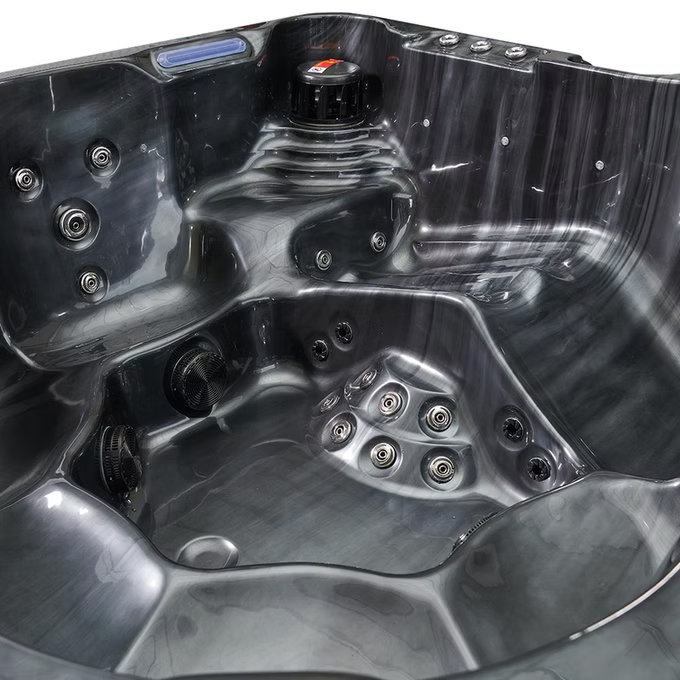 Black plastic hot tub with multiple jet nozzles and a central control panel.