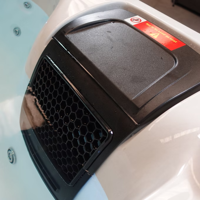 Black honeycomb grille with a matte finish, set into the white plastic housing of an electric scooter.