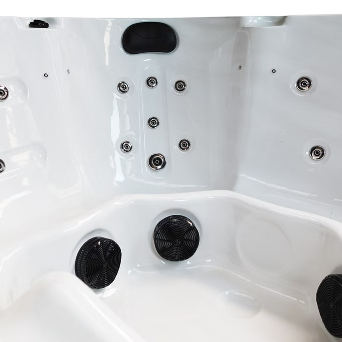 White hot tub with black jet nozzles and circular filters.