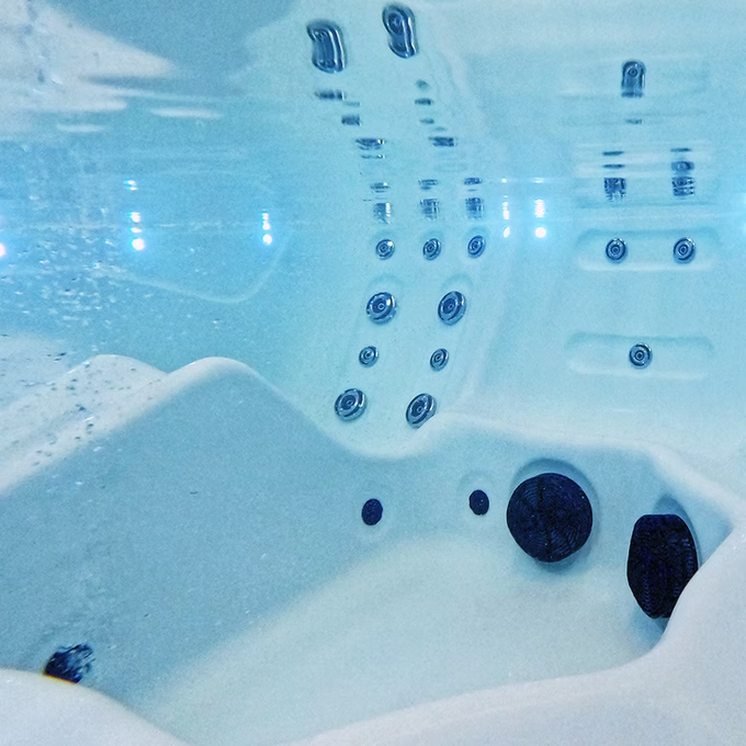 White hot tub with blue water and black jets.