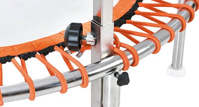 Orange elastic cords secure a silver metal trampoline frame with black adjustment knobs.
