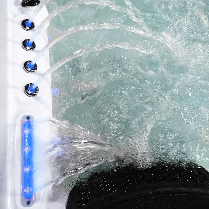White hot tub with blue led lighting and multiple water jets.